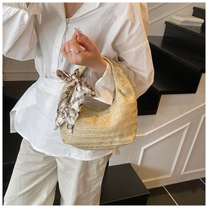 Détail d'un sac hobo en paille tressée avec foulard en soie et motif ondulé élégant