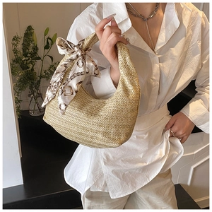 Détail d'un sac à main en paille tressée avec foulard en soie et forme en croissant