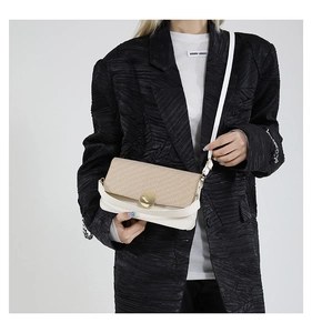 Detail of contrast stitch handbag with gold buckle on a model in a black blazer