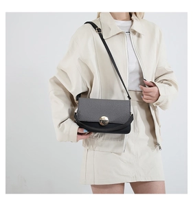 Detail view of contrast stitching and gold twist lock on women's crossbody bag