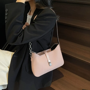 Pink woven texture shoulder bag with silver chain strap worn by a model in black blazer