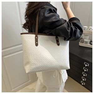 Detail of white woven leather tote bag with brown shoulder straps on a model in-home