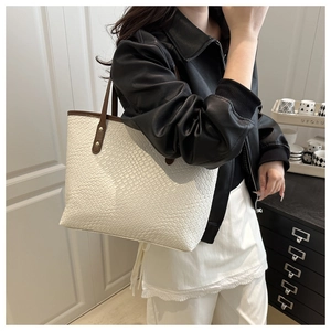 Detail of white woven tote bag with brown leather straps and gold rivets for women
