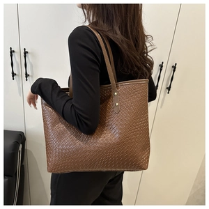 Close-up of the brown woven leather texture and golden metal rivets on the tote bag