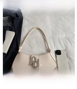 Detail view of cream leather underarm bag featuring silver PD metal buckle and thin strap