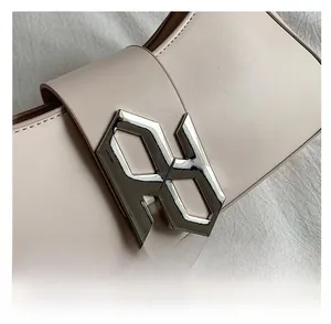 Detail of a chic beige underarm bag featuring a geometric silver metallic buckle closure