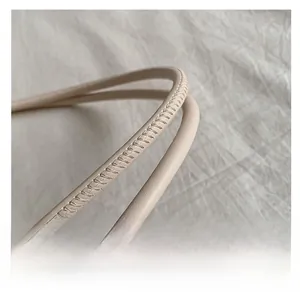 Macro view of beige leather handle with precise white stitching details on stylish handbag