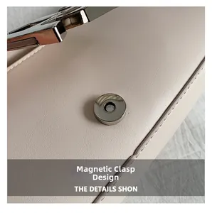 Detailed macro view of the smooth metallic magnetic buckle on a beige leather handbag