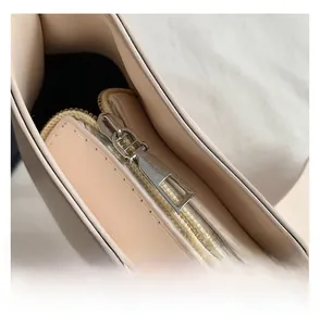 Detail view of smooth silver metal zipper and neat stitching on cream leather handbag