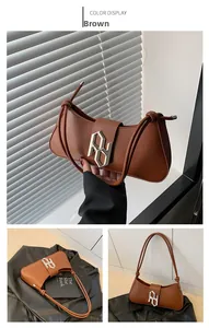 Detail of silver geometric buckle and leather texture on a brown half-moon bag