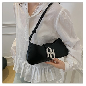 Detail of elegant black shoulder bag with silver geometric buckle on white blouse