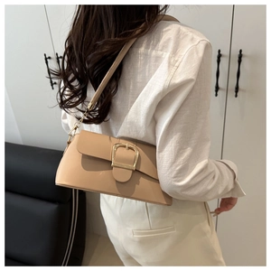 Detail of minimalist beige faux leather bag featuring a large gold metal buckle closure