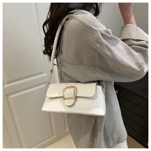 Close-up of white underarm bag with large gold metal buckle and leather chain strap