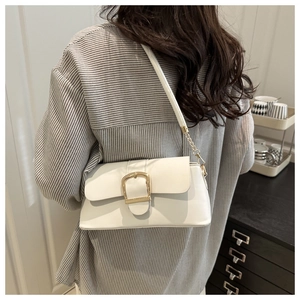Detail of cream shoulder bag with gold buckle and chain strap on a model's arm