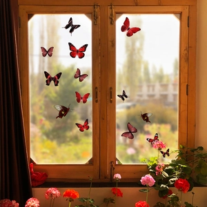 Detailed view of realistic red butterfly window stickers on a glass pane in a cozy room