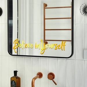 Détail du sticker mural miroir doré 'Believe in Yourself' sur carrelage blanc