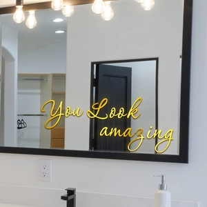 Gros plan du sticker mural miroir doré avec texte You Look Amazing dans une salle de bain