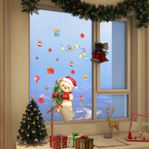 Close-up of cute Christmas bear and festive decals on a window with city night view
