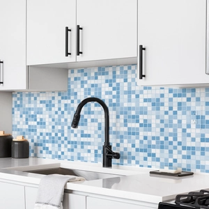 Detail of blue and white mosaic wall tiles in a kitchen with a modern black faucet
