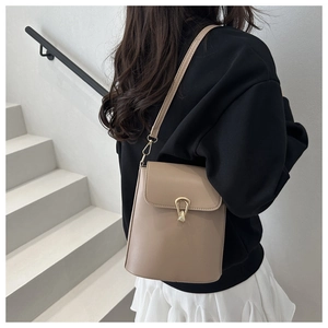 Vue détaillée du sac seau beige avec fermoir doré sur un mannequin en noir