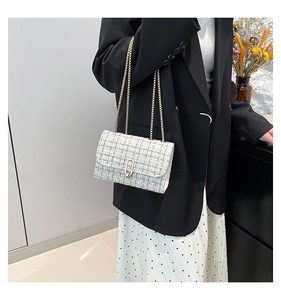 Détail du sac bandoulière en tweed avec boucle dorée et texture tissée élégante