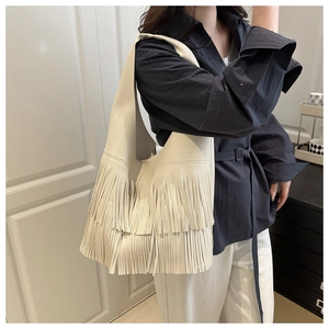 Close-up of cream shoulder bag with stylish fringe detail and pebbled texture