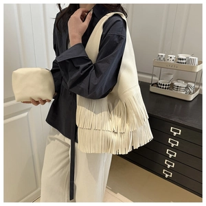 Close-up of beige faux leather tote bag with tiered fringe detail and matching pouch