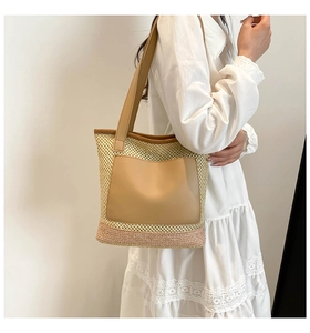 Close-up of woven straw tote bag with brown leather pocket and reinforced base