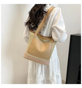 Detail of woven straw tote bag with brown leather pocket and wide shoulder strap