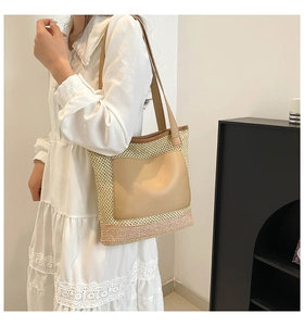 Detail of woven straw tote bag featuring brown leather pocket and long shoulder straps