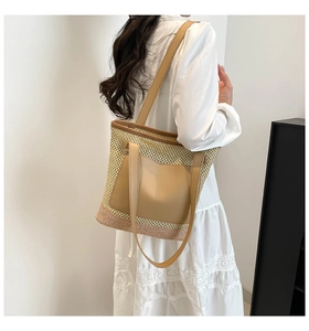 Detail of hand-woven straw tote bag showing contrast colors and brown leather pocket
