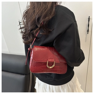 Détail du sac bordeaux à motif crocodile avec une boucle en fer à cheval dorée