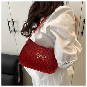 Détail du sac rouge à texture circulaire gaufrée avec boucle en métal noeud doré