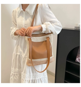 Detail of straw tote bag showing brown leather straps and woven texture for beach use