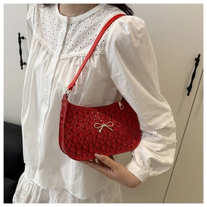 Close-up of red bubble textured faux leather bag with a gold metal bow detail