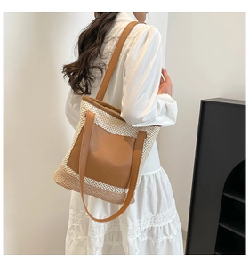 Detailed side view of a large woven tote bag featuring a leather pocket for women
