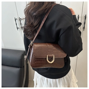 Vue détaillée du sac à bandoulière marron foncé à motif crocodile avec boucle dorée en D