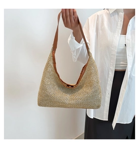 Close-up of the delicate hollow-out weave and brown leather strap of the straw tote bag