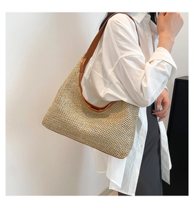Close-up of woven straw tote bag with brown leather straps and detailed mesh texture