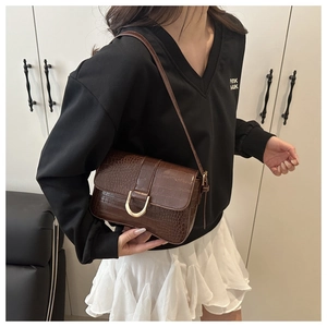 Détail du sac bandoulière marron foncé à texture pierre avec boucle magnétique dorée