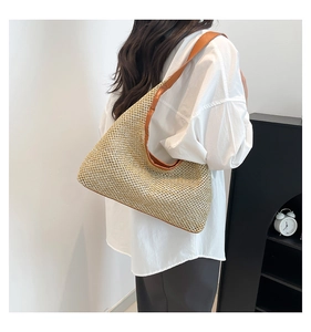 Detail of hand-woven straw beach bag with premium brown leather shoulder strap on a model