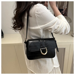 Détail de la texture crocodile et boucle fer à cheval dorée sur le sac à bandoulière noir
