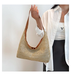 Detail of woven straw shoulder bag with brown leather trim and sturdy strap design