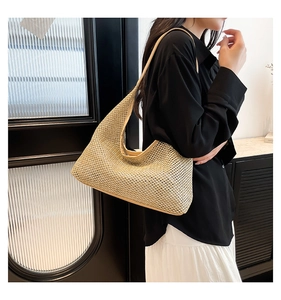 Detail of hand-woven straw hobo bag showing the delicate mesh texture and slender strap