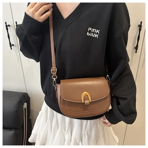 Détail d'un sac selle marron avec une boucle métallique élégante en forme de U doré