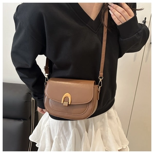Détail d'un sac besace marron classique avec boucle fer à cheval dorée sur cuir mat