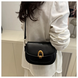 Detalle de un bolso de montura negro con hebilla de herradura dorada en cuero mate fino