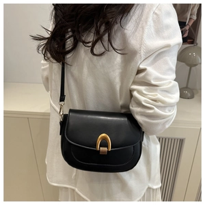 Mannequin portant un sac besace noir avec boucle dorée sur un fond au style minimaliste