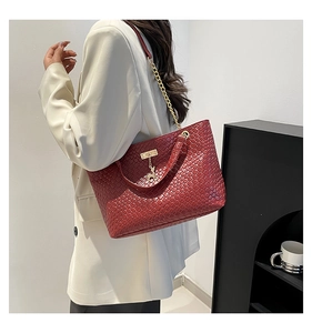 Detail of dark red woven tote bag featuring gold chain strap and deer charm accessory