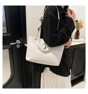 Detail of white woven texture tote bag with gold chain strap and deer charm